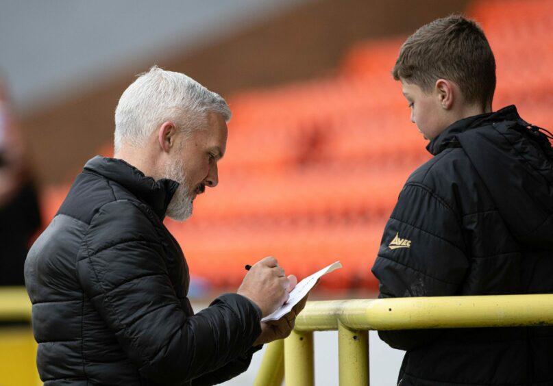 Jim Goodwin signs autograph for young fan.