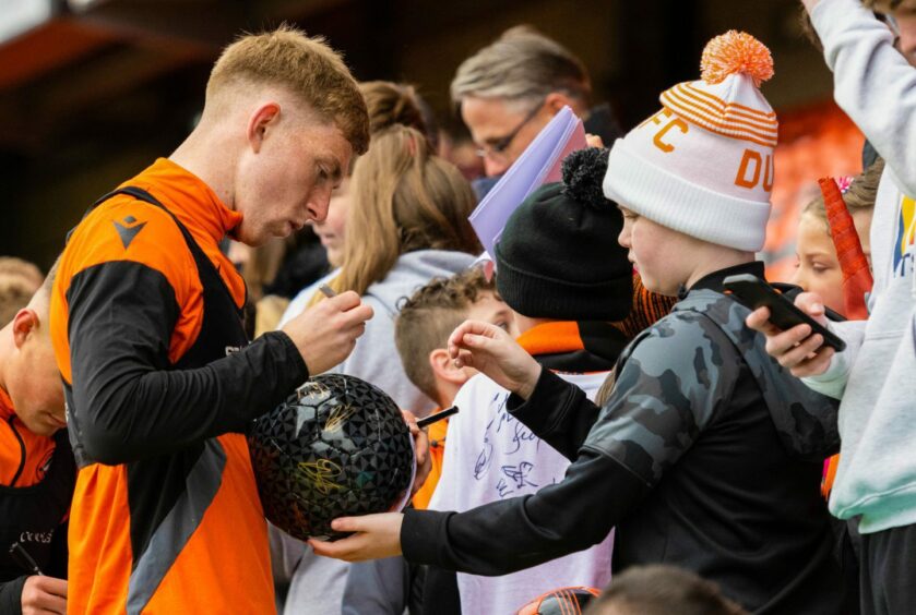 Kai Fotheringham signs football for young Dundee United fan at open training session.