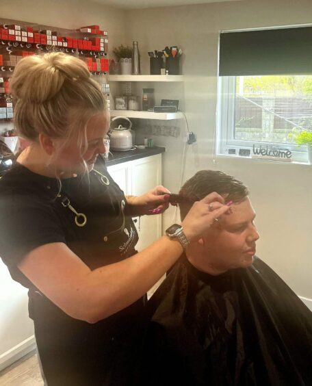 Andrew Batchelor getting a haircut from Karen Ward