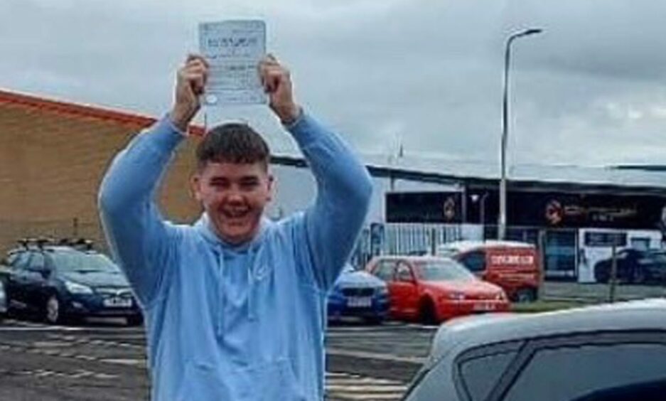 Cameron holding his certificate for passing his driving test. 