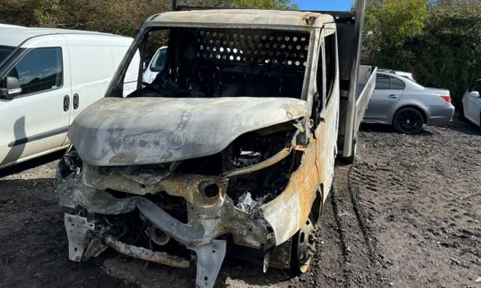 Front view of the torched vehicle with severe fire damage.