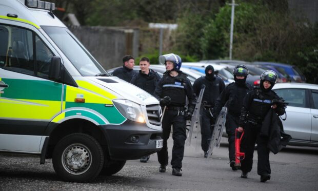 Police in riot gear arrive at the scene. Image: David Wardle