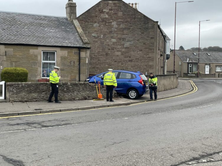 Car crashed through garden wall of house on Barry Road, Carnoustie, surrounded by police.