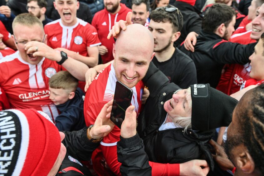 Brechin City's Euan Spark in a large scrum of fans after the game.