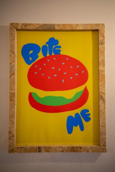 Art featuring burger with 'bite me' written on it, hung up on a wall in Vandal & Co Perth