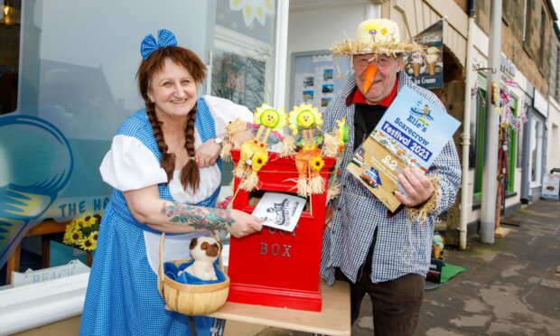 Brenda Smith and Ron Howie from the local care home post their entries for the scarecrow hunt in the post box.