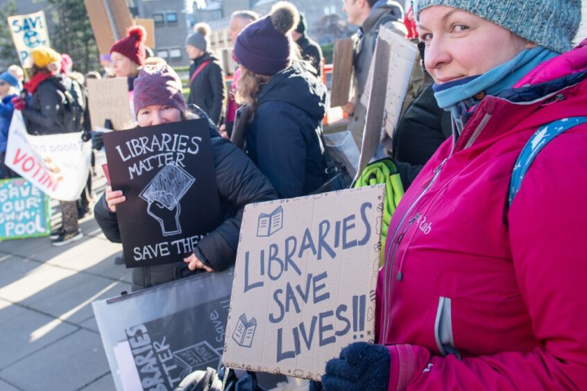 Campaigner holding a placard which reads 'Libraries save lives'.