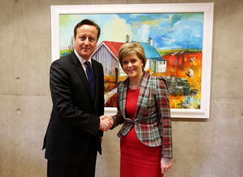 Nicola Sturgeon and David Cameron shaking hands in front of a painting.