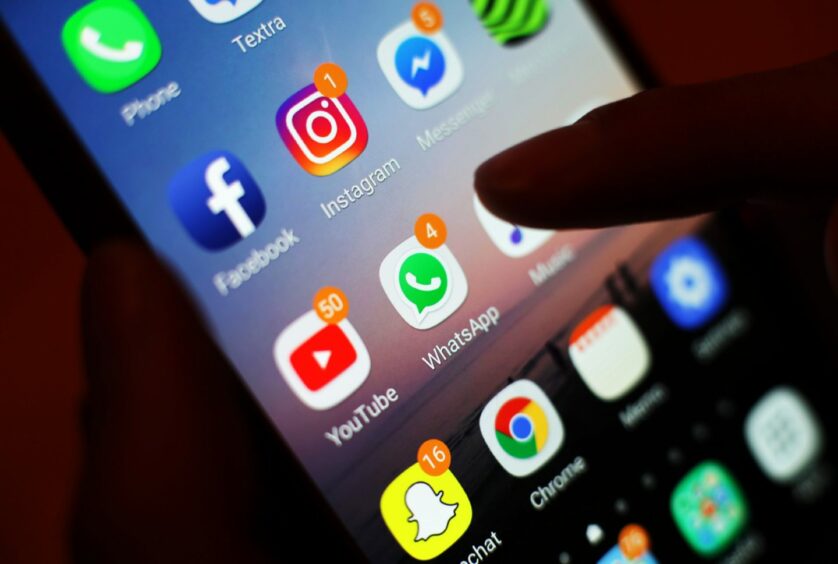 finger hovering over a mobile phone screen showing WhatsApp and Snapchat icons.