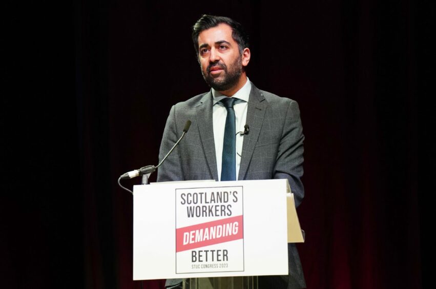 Humza Yousaf behind a podium with the slogan 'Scotland's workers demanding better'.