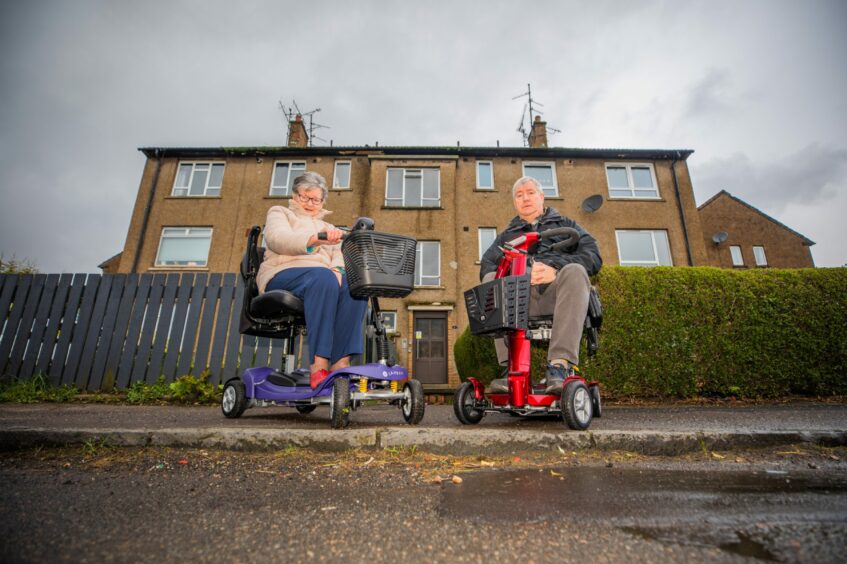 Image shows Nan who wants to see more dropped kerbs in Dundee with her son, Robert, both using mobility scooters. 