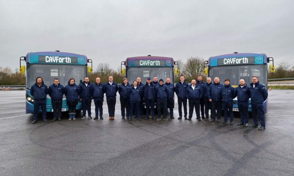 Three CavForth autonomous buses in Fife, with staff members stood in front of the vehicles in their uniforms. 