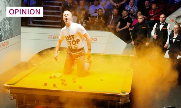 Just Stop Oil protester on a snooker table in a cloud of orange powder