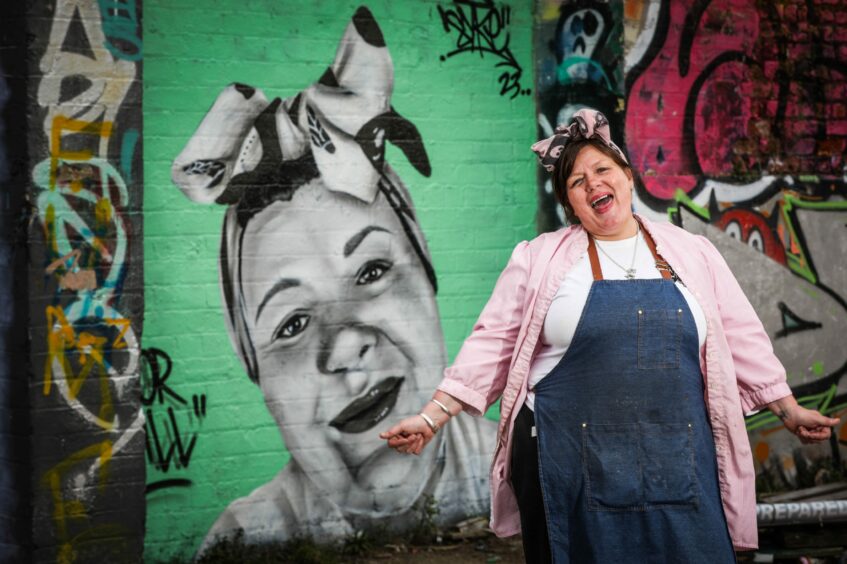 Gill Young, owner of The Shack Street Food, beside Syke mural of her on Mary Ann Lane. 