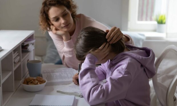 Parent with girl at desk helping her deal with exams stress.