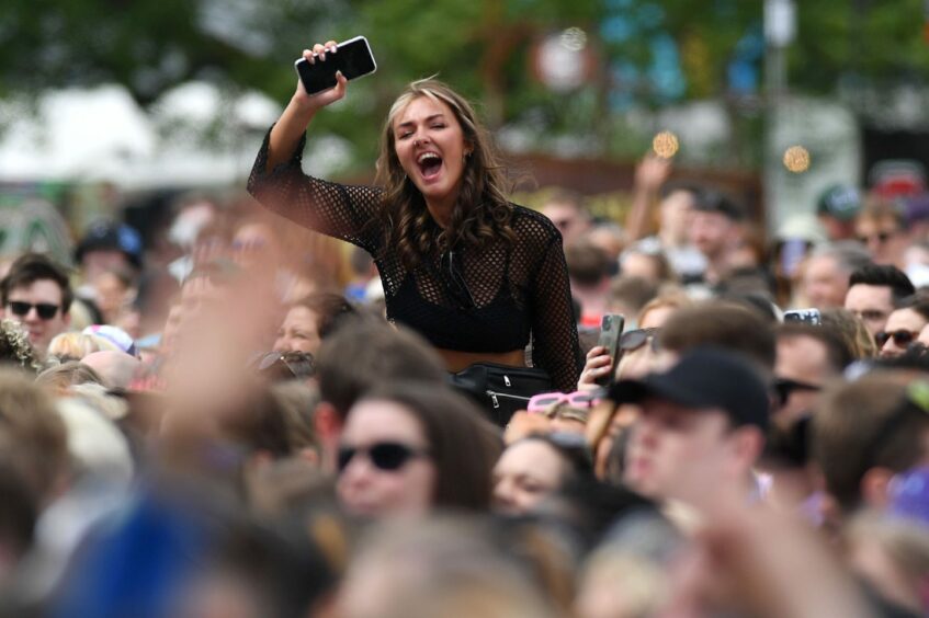 Revellers cheering as the Jonas Brothers take to the stage. 