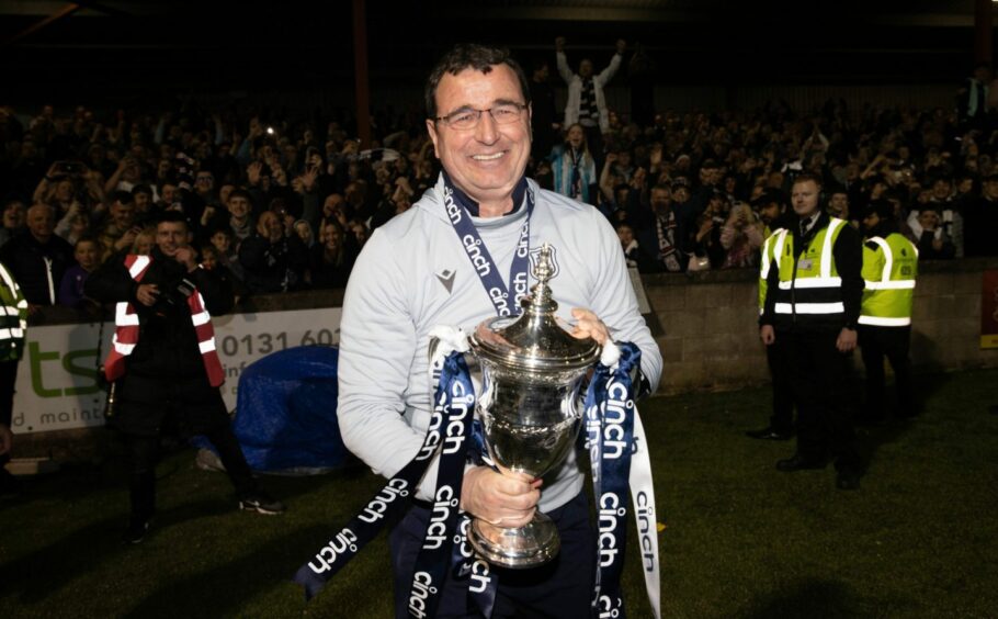 Beaming Dundee boss Gary Bowyer holds the Championship trophy.