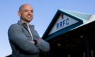 Raith Rovers director Ruaridh Kilgour stands with his arms folded at a sunny Stark's Park.