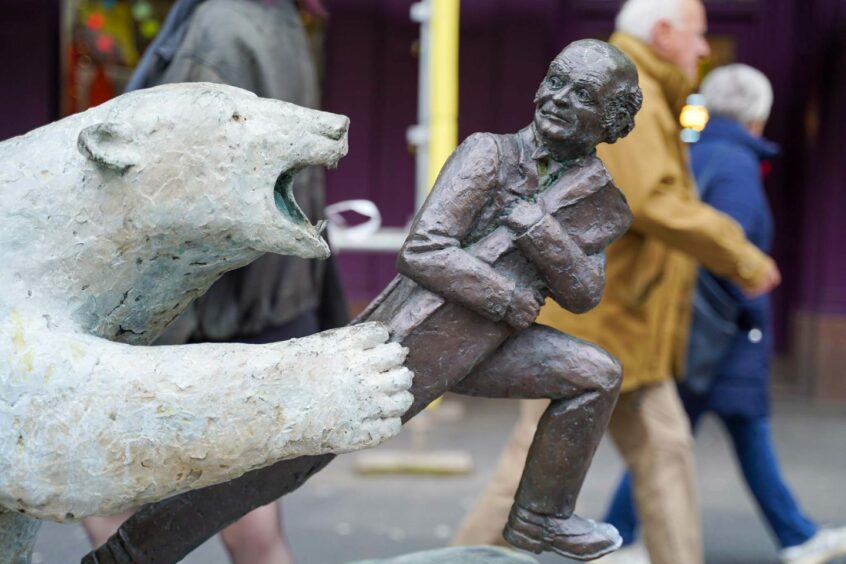 Statue of man being chased by a polar bear on a Dundee street.