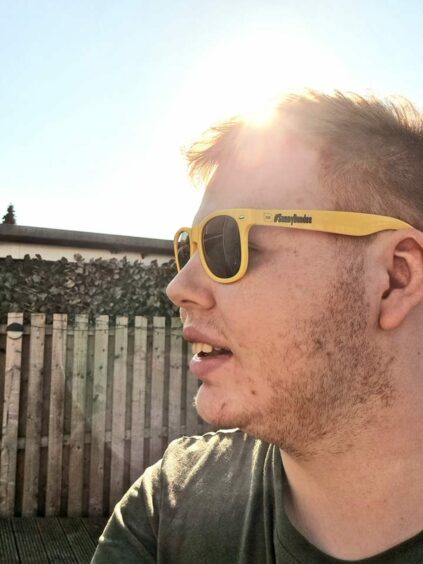Andrew Batchelor in profile, wearing yellow sunglasses with Sunny Dundee logo.