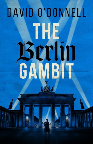 The image shows the cover of The Berlin Gambit by David O'Donnell. The cover has a blue background with an image of Berlin's Brandenburg Gate in silhouette and searchlights crossing the image.