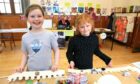 Amelia Gault and Isabel Laing try their hands at making a crown at the big lunch. Image: Phil Hannah.