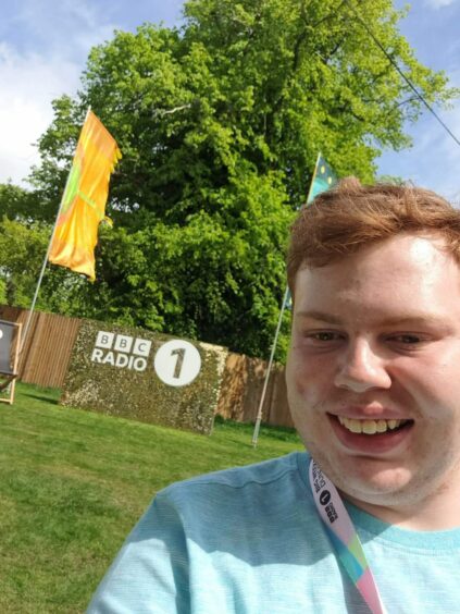Andrew Batchelor in front of a BBC Radio 1 sign at Big Weekend Dundee in Camperdown park.