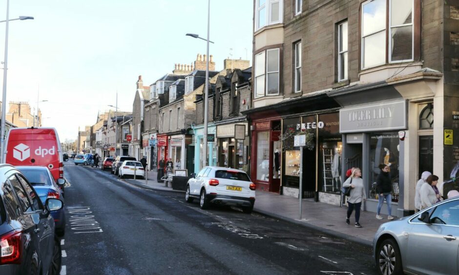 view of Broughty Ferry with parked cars and pedestrians.