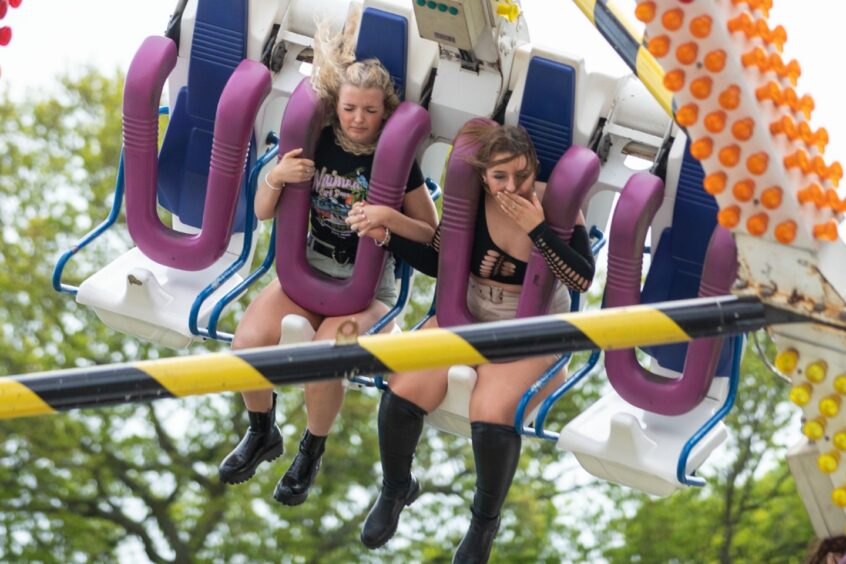Two women hold hands and close their eyes as they brave one of the rides at Camperdown Park.