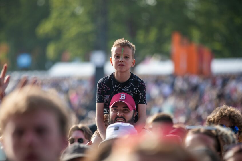 A boy on a man's shoulders watching Radio 1's Big Weekend in Dundee