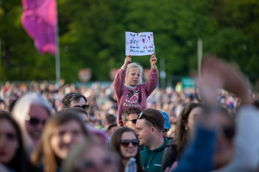 A youngster holding up a sign for Niall Horan, which reads he is her first live gig.