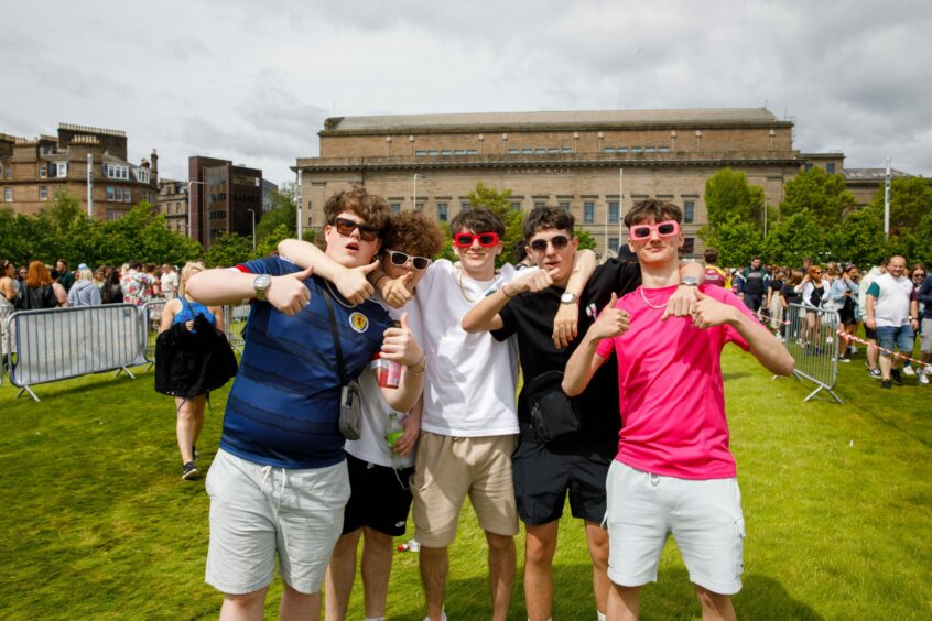 Group of boys sporting sunglasses as they wait to catch a shuttle.