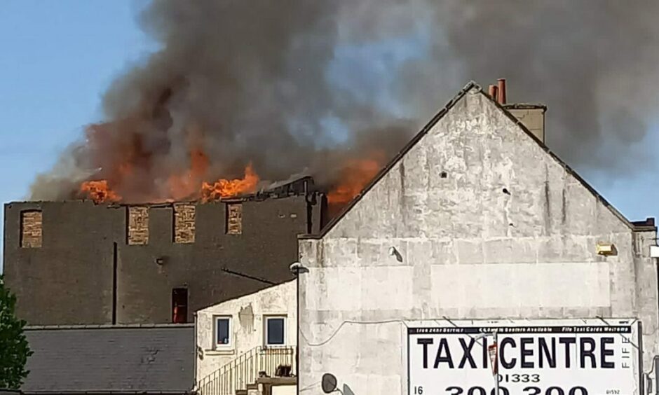 Smoke and flames shoot through the roof of the building