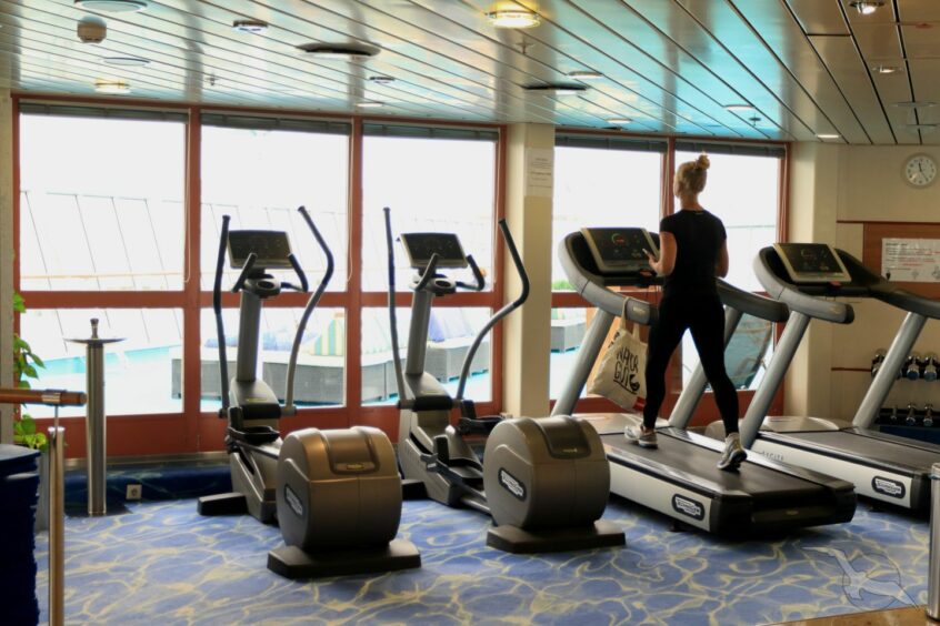 A woman using a treadmill on the ship.