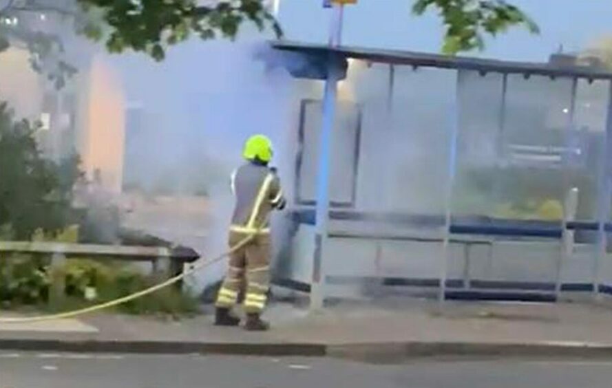 Firefighter putting out a fire at a bus stop on Alexander Street in Dundee
