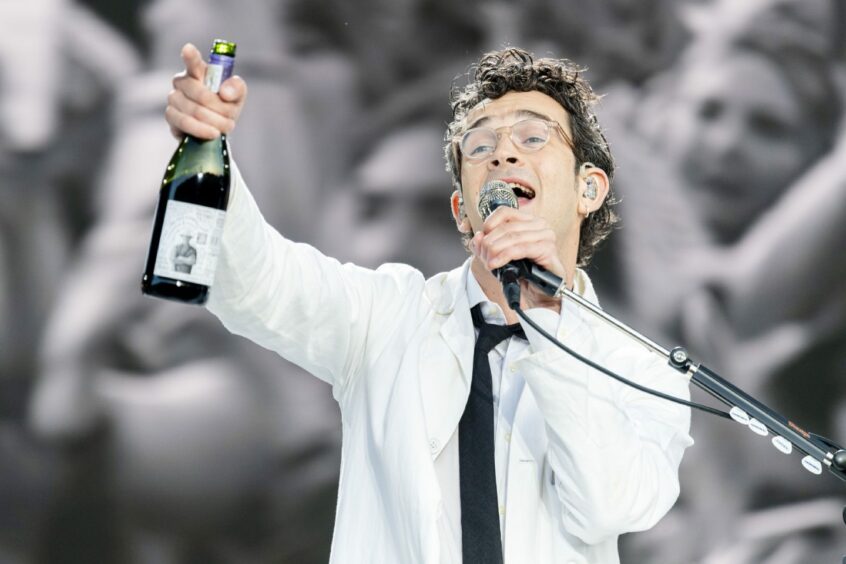 The 1975 singer Matt Healy holding a bottle of alcohol and singing at Radio 1's Big Weekend in Dundee