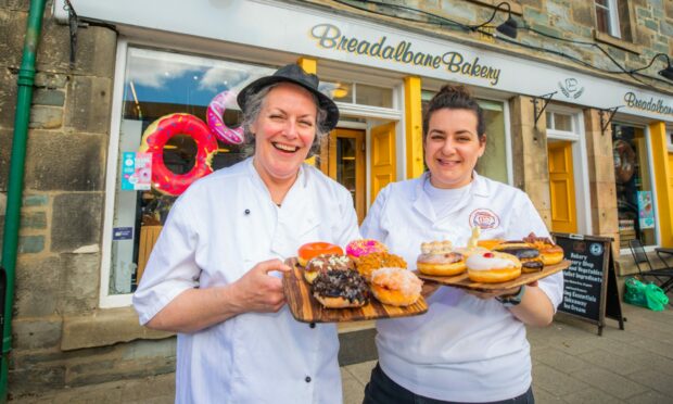 Two women holding trays of doughnuts outside Breadalbane Bakery in Aberfeldy