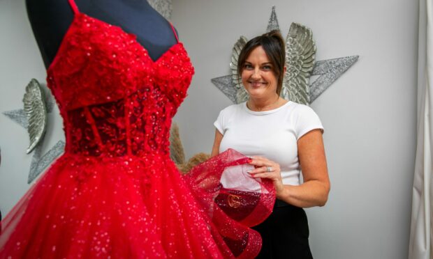 Star Bridal Boutique owner Jackie Effron with a red prom dress.