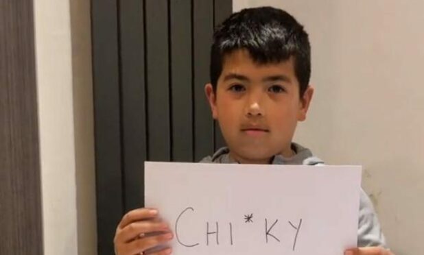 Ethan To holding up a sign of one of the racist words he has been called at school. Image: Mason To/TikTok