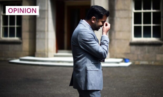 Humza Yousaf in profile holding his hand to his head.