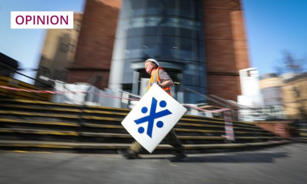 workman removing Bank of Scotland sign from closed branch in Dundee.