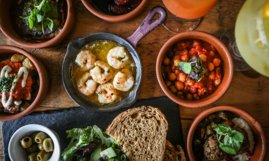 A selection of small tapas plates, including gambas pil pil, chickpea salad, olives and bread.