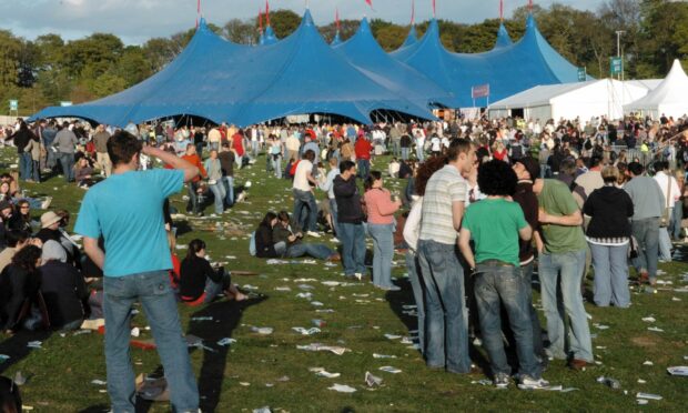 2006 Big Weekend in Dundee's Camperdown Park. There are fans standing on the grass with litter at their feet.