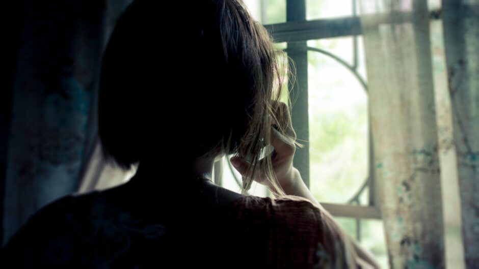 woman talking on phone, silhouetted in front of a window