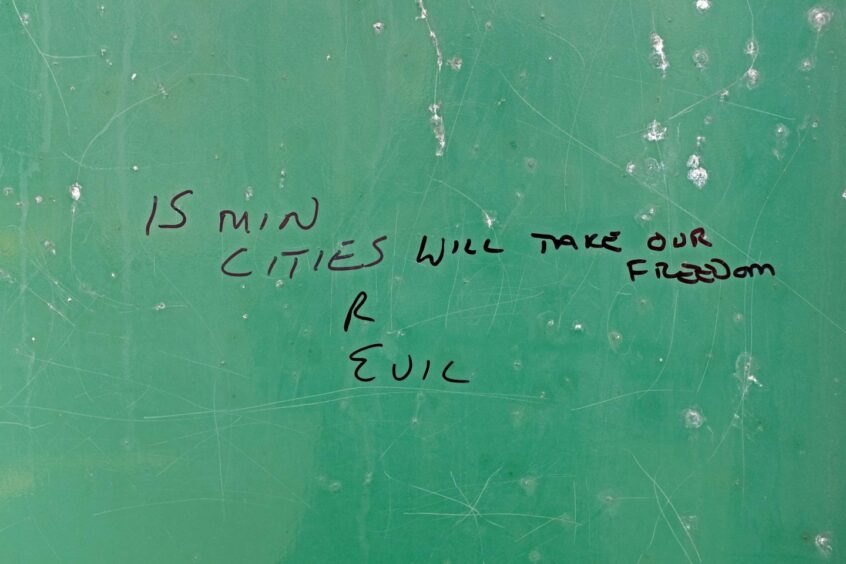 Bus shelter graffiti which reads '15 min cities r evil will take our freedom'