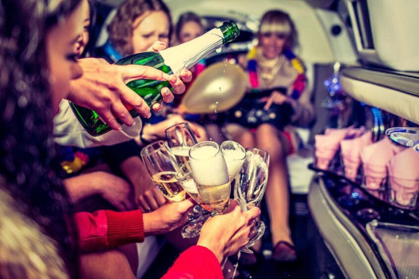 Group of women drinking sparkling wine in a limo