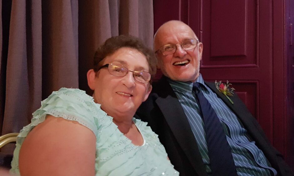 Photo of a smiling couple in their 60s at a wedding reception.