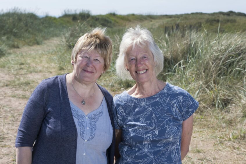 Wendy and Anne standing at the coast beside Carnoustie Gold Course in the sunshine. They have been working to protect the Small Blue butterflies in Angus since 2016. 