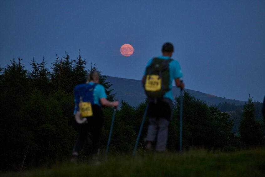 Two walkers on the Cateran Yomp with the moon above them