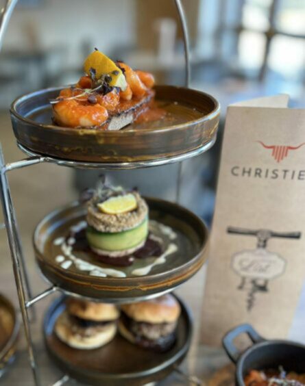 Tower of tapas in Christie's restaurant. Chicken on top, an avocado dish in the middle. The menu in the background.